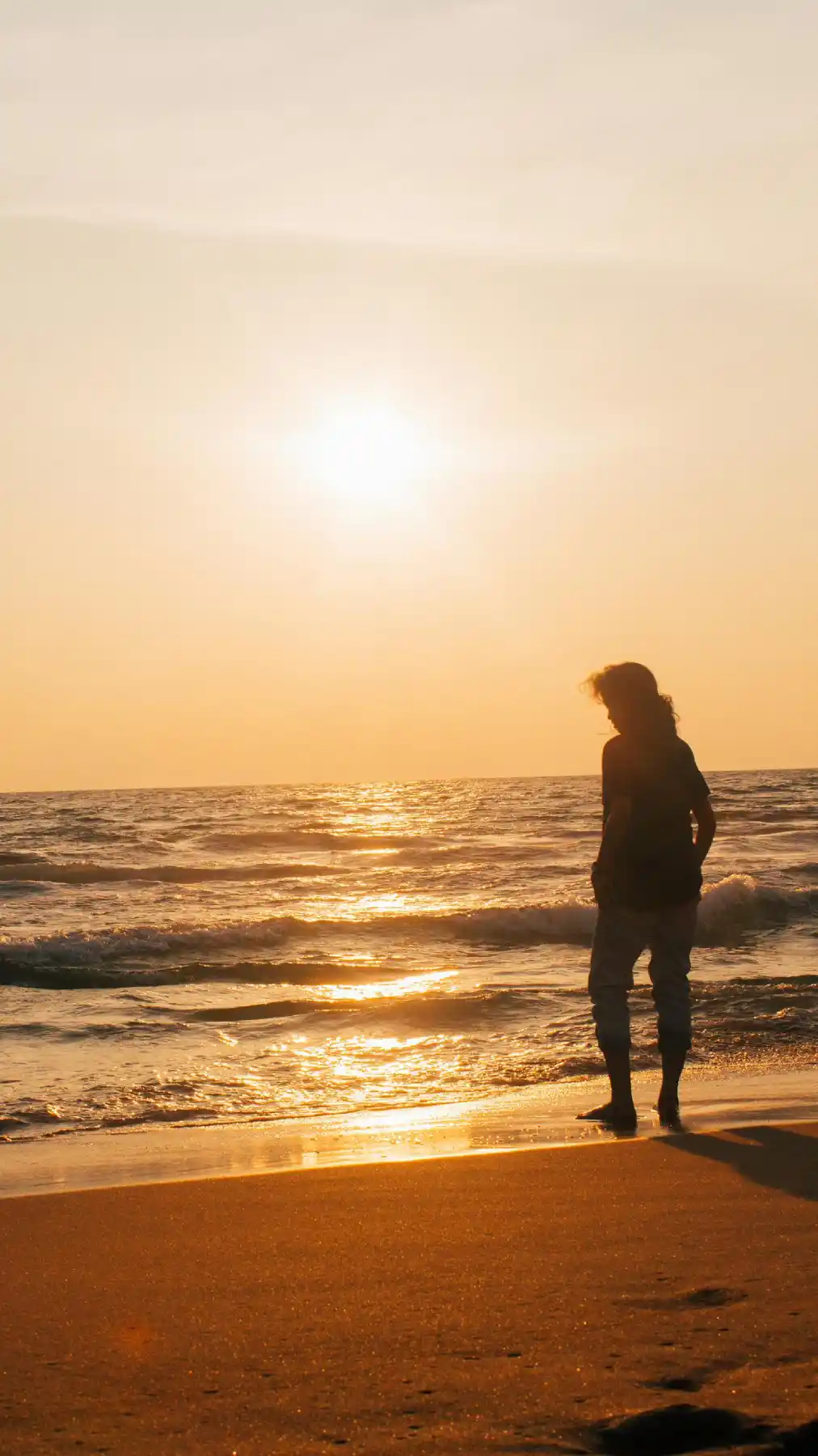 Person walking by the ocean at sunset, reflecting on life.